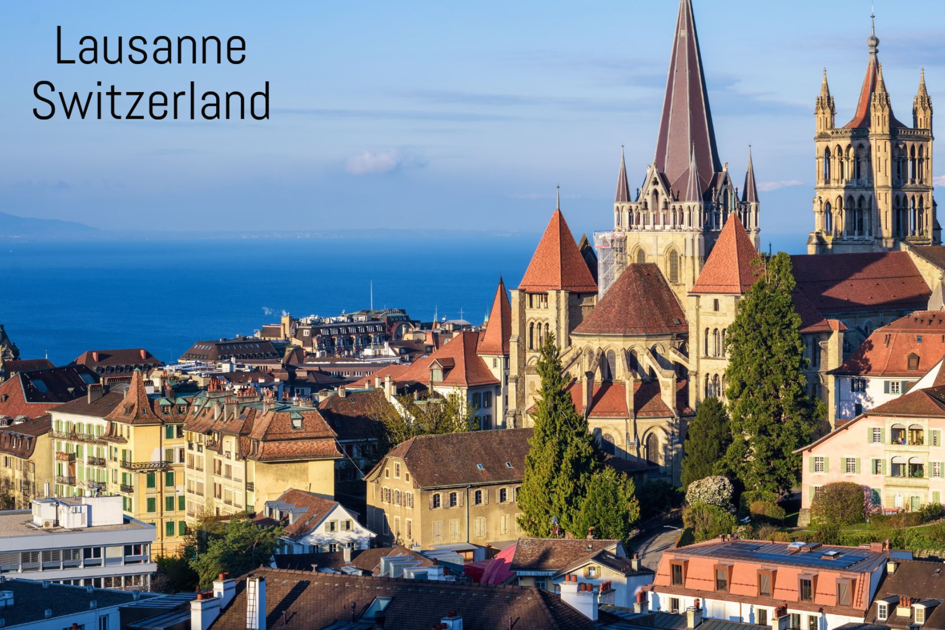 Scenic view of Lausanne, Switzerland, featuring Lausanne Cathedral and rooftops with Lake Geneva in the background