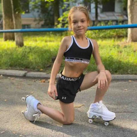 Маленькая девочка в роликовых кроссовках и спортивный летний костюм